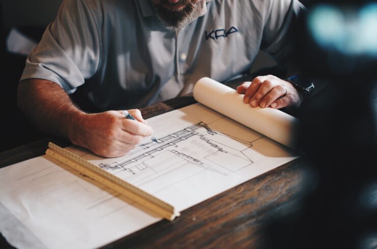 Hands drafting architectural plans with a pencil and ruler