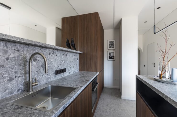 Finished wood cabinetry, stone counters and a fitted sink in a compact modern kitchen.