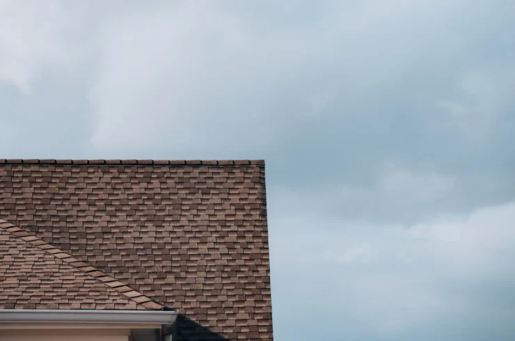 Brown asphalt shingle roof and white gutter beneath a blue sky.
